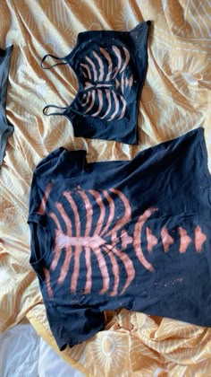 two pieces of clothing are laying on a bed with an orange and black design painted on them