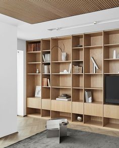 a living room filled with lots of wooden bookshelves next to a white wall