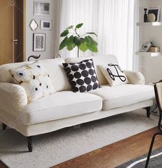 a living room with white couches and black and white pillows