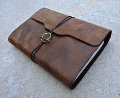 a brown leather journal sitting on top of a cement floor