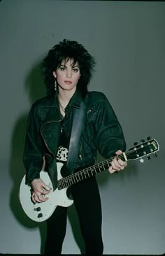 a woman with black hair holding a white guitar