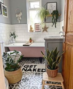 a bathroom with potted plants on the floor and a bathtub in the background