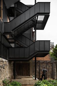 a man standing in front of a building with stairs leading up to the second floor