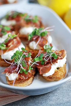 small appetizers are arranged on a plate with lemons in the back ground