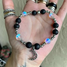 Bead / Gemstone / Boho / Oil Diffuser / Oil Diffusing / Fits 6 To 7.5 Inch Wrist ( If You Need A Different Size Lmk ! ) Handmade By Me Genuine 8mm Oil Diffuser Black Lava Rock Beads . 8mm Opalite Man Made Iridescent Beads (4) . Stainless Steel & Silver Plated Spacers . Silver Plated Dangly Moon Charm / Gift / Stylish , Gems , Trendy , Dainty , Bohemian / Bohochic / Stack Bracelets / Beaded Bracelets / Gemstones / Crecent Moon / Moon Child / Moon Phase . Ceystal Bracelets, Beaded Charm Bracelets Diy, Alt Beaded Bracelets, Green Glass Bead Bracelet, Lava Bracelet Ideas, Gothic Beaded Bracelet, Lava Bead Bracelet Ideas, Beaded Gemstone Bracelets, Beaded Charm Bracelet Ideas