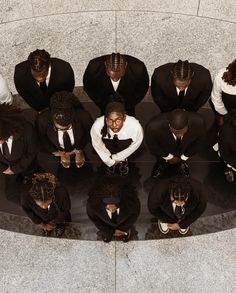 a group of people in suits sitting on top of a floor next to each other