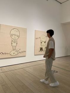 a man standing in front of two cartoon drawings on the wall next to each other