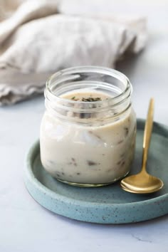 a glass jar filled with food sitting on top of a plate next to a spoon