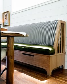 a wooden bench sitting on top of a hard wood floor next to a table and chair