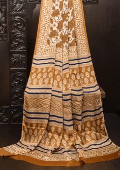 This product features the Ajrakh Hand Block Floral Print on Modal Silk in Statement Beige and Mustard, showcasing the intricate and traditional craftsmanship of the region. Made with high-quality materials and attention to detail, this piece is a perfect addition to any wardrobe. The saree is ready to wear with falls and pico done. An unstitched blouse fabric is included.  *Note: There may be minor variations in the shade, the texture of the product. Hues/textures show differently due to variations in screen settings and other factors, *Note: This is a handmade product involving mineral and vegetable dyes that are printed by hand. There may be slight inconsistencies owing to the human made nature of it and these are not considered defects. Ajrakh Sarees Online, Human Made, Printed Saree, Printed Sarees, Blouse Fabric, Scarf Styles, Mustard, Favorite Outfit, Ready To Wear