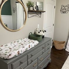 a baby's crib and dresser in a room with a mirror on the wall