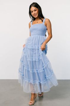 a woman is wearing a blue dress with tiered ruffles on the bottom