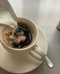 a cup of coffee with milk being poured into it