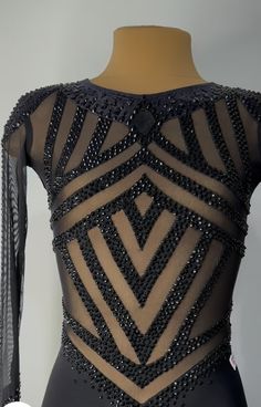 the back of a black dress with beading and fringes on display in front of a mannequin