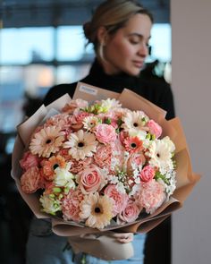 a woman holding a bouquet of pink and white flowers