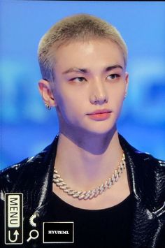 a young man with blonde hair wearing a black leather jacket and silver necklace on top of his head