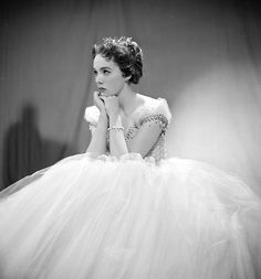 a black and white photo of a woman in a tulle dress with her hands on her face