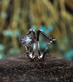 two silver rings with blue topazte and white diamond accents sitting on a rock