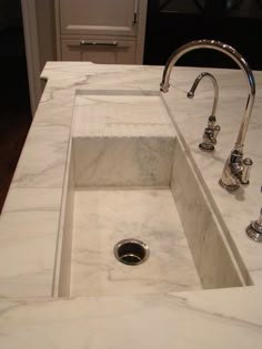 a white sink sitting under a faucet on top of a marble countertop