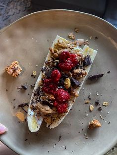 a person holding a plate with some food on top of it, including bananas and raspberries