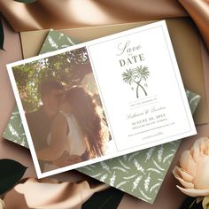 an image of a save the date card on top of some papers with flowers and leaves around it