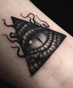 a black and white photo of a triangle with an eye inside it on someone's leg