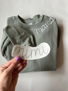 a person holding up a paper cut out of a t - shirt with the word mama on it