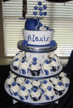 a tiered cake with cupcakes on it is decorated in blue and white