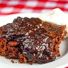 a piece of chocolate cake on a white plate with ice cream and red checkered table cloth