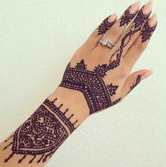 a woman's hand with henna tattoos on it and a diamond ring in the middle