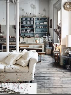 a living room filled with furniture and lots of shelves on the wall next to a window