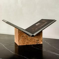 an open book sitting on top of a marble block with a black and white cover