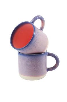 two purple and white coffee mugs stacked on top of each other with red liquid in them