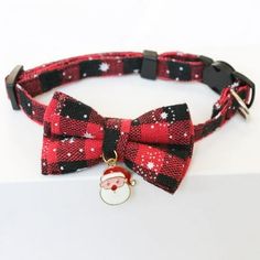 a red and black bow tie with a santa claus charm on the front, sitting on a white surface