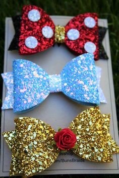 three glitter bow hair clips with red, blue and gold sequins on them