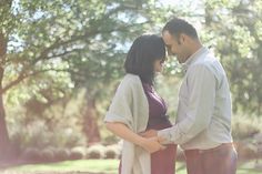 a man and woman standing next to each other in front of trees with the sun shining on them