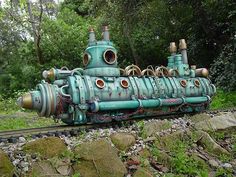 an old train engine is sitting on the tracks near some rocks and grass, with trees in the background