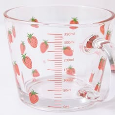 a measuring cup with strawberries printed on the front and sides, sitting on a white surface