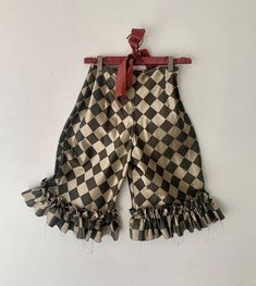 a black and white checkered shorts hanging on a clothes hanger with a red ribbon