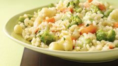 a bowl filled with rice, broccoli and carrots on top of a wooden table