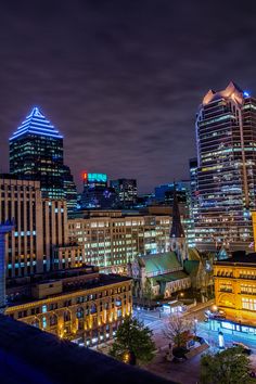 the city skyline is lit up at night, with skyscrapers in the foreground