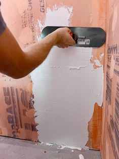 a person holding a skateboard in front of a wall that has been torn down