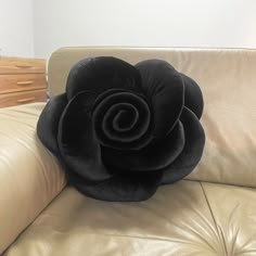 a black rose pillow sitting on the back of a leather couch in a living room