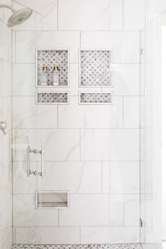 a white tiled shower with two shelves on the wall