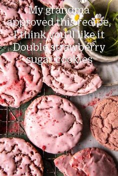 several cookies with pink icing sitting on a cooling rack