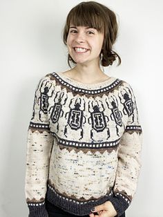 a smiling woman wearing a sweater with an ugly pattern on the front and back, standing in front of a white background