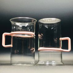 two glass mugs sitting next to each other on a table