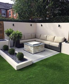 an outdoor living area with grass, couches and potted trees in the middle