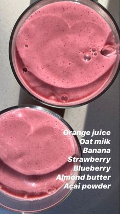 two glasses filled with pink smoothie sitting on top of a white counter next to each other