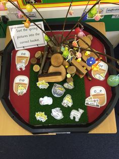 a tray with various items on it sitting on a table in front of a sign that says, sort the spring pictures into the correct book